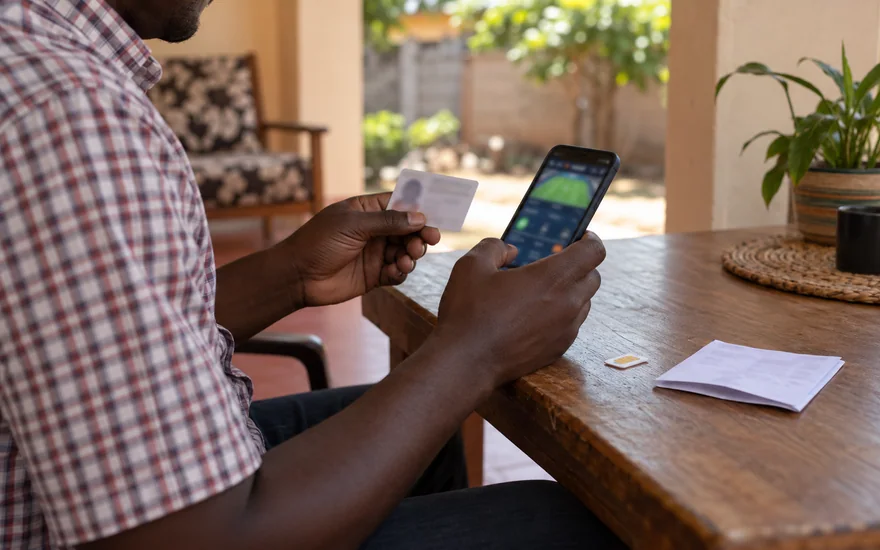 betPawa verification payment ownership scene with a blurred betting receipt, unmarked SIM card and phone at a Zambian agent counter.