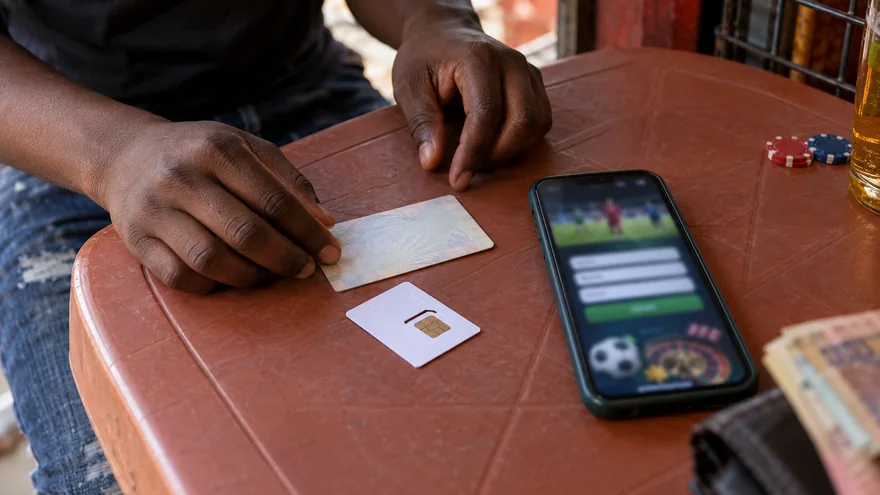 betPawa registration preparation at a Lusaka SIM kiosk with a glowing betting phone, blank document sleeve and unreadable betting slip