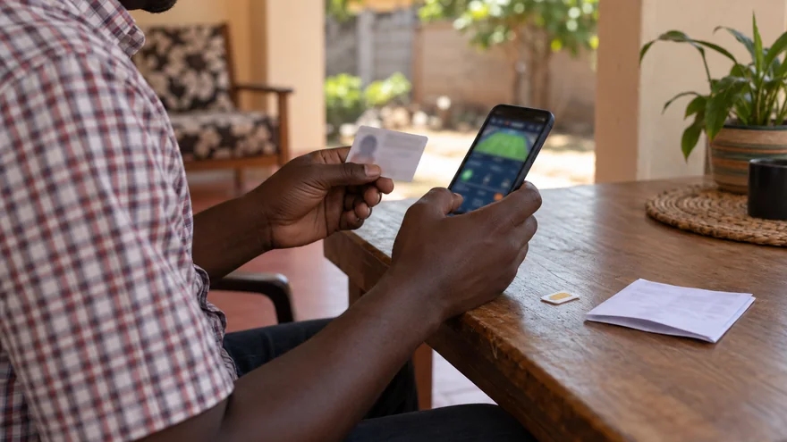betPawa verification payment ownership scene with a blurred betting receipt, unmarked SIM card and phone at a Zambian agent counter.